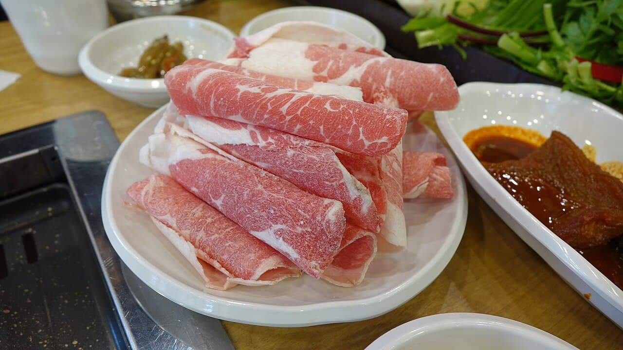 Các lát 차돌박이 thịt ức bò thái mỏng và cuộn tròn trên đĩa trắng tại nhà hàng nướng