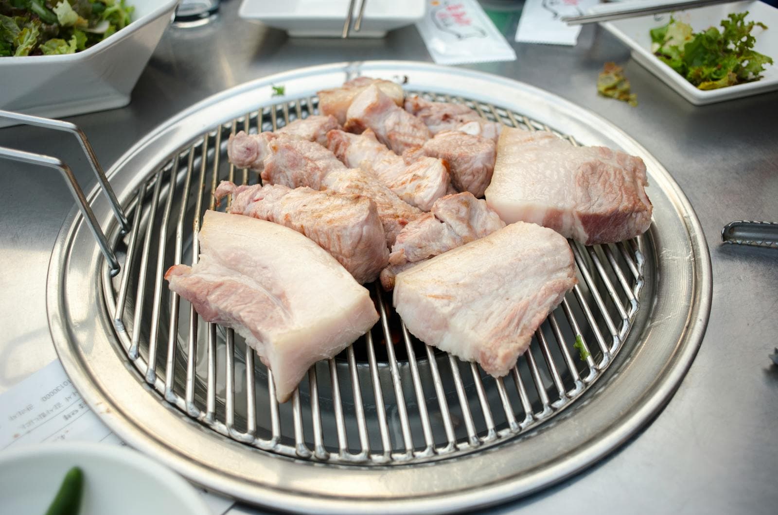 Các miếng 오겹살 dày còn nguyên da trên vỉ nướng